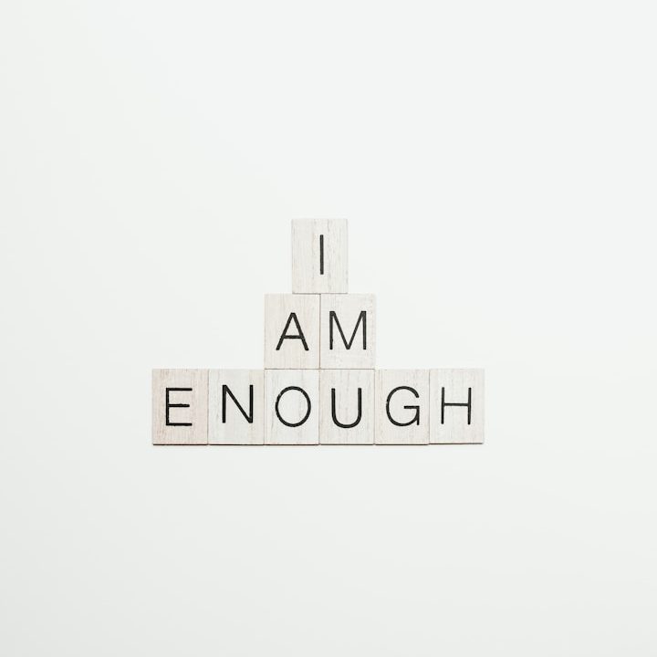 Selbstwert stärken bei Kindern und Jugendlichen – therapeutische Begleitung Schriftzüge "I AM ENOUGH" in Blockbuchstaben auf hellem Hintergrund.
